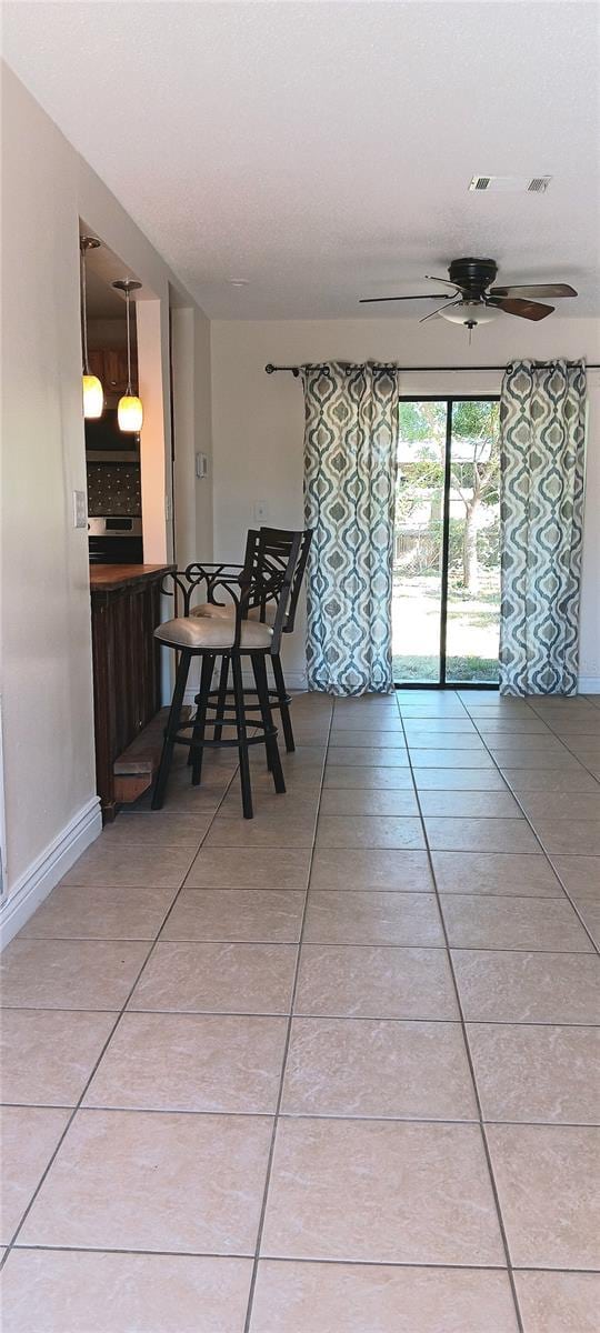 unfurnished dining area with ceiling fan and light tile patterned flooring