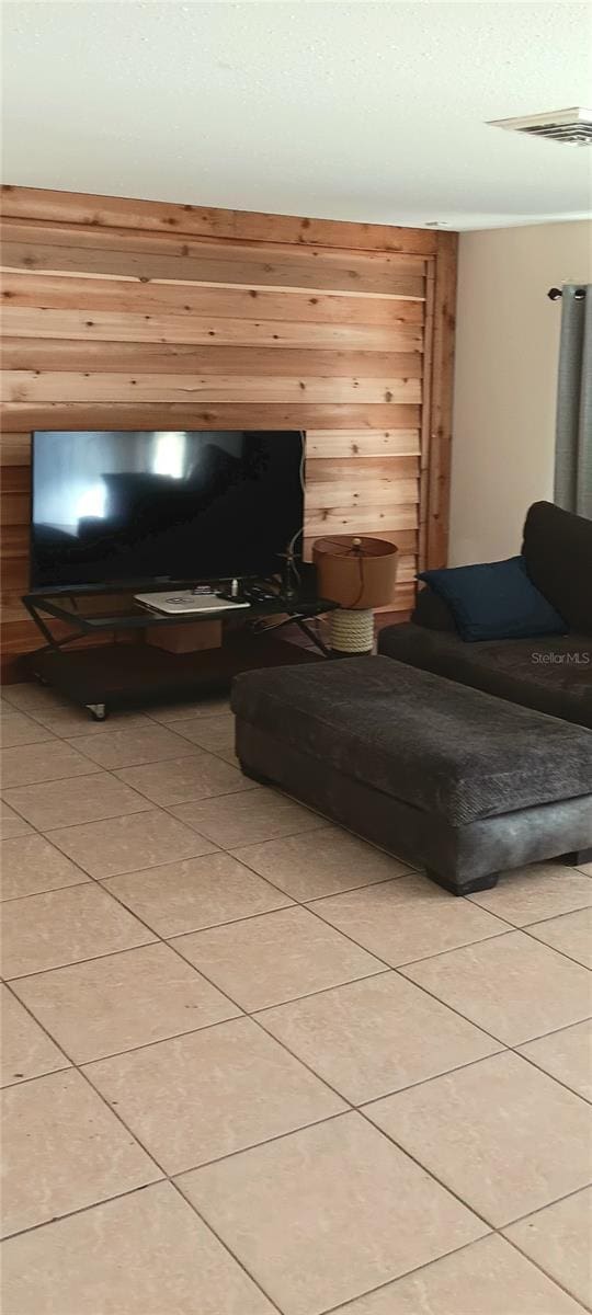 unfurnished living room featuring light tile patterned floors and wooden walls