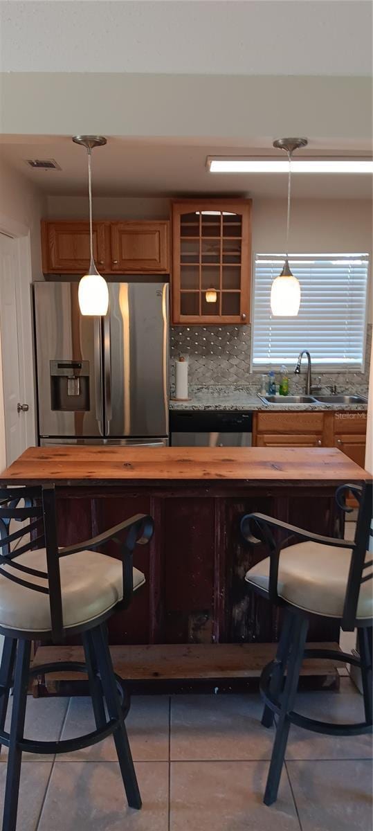 bar featuring appliances with stainless steel finishes, tasteful backsplash, sink, light tile patterned floors, and hanging light fixtures