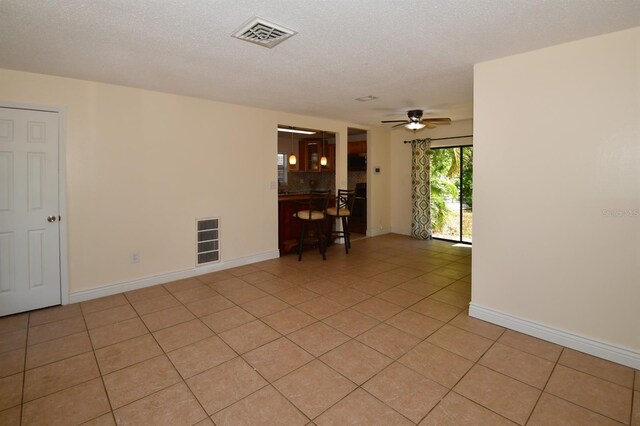 empty room featuring visible vents, a textured ceiling, baseboards, and light tile patterned floors