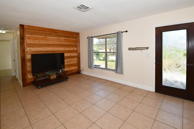 unfurnished living room with visible vents, a textured ceiling, baseboards, and light tile patterned flooring