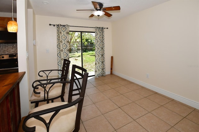 dining area with ceiling fan, baseboards, and light tile patterned floors