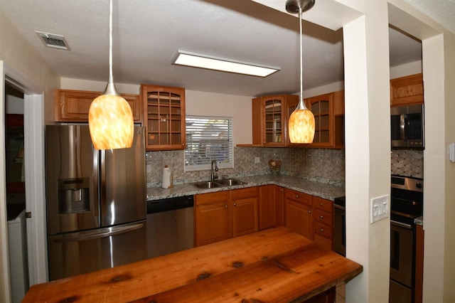 kitchen with tasteful backsplash, visible vents, brown cabinetry, stainless steel appliances, and a sink