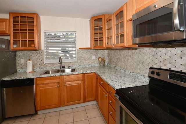 kitchen featuring light stone countertops, appliances with stainless steel finishes, a sink, and light tile patterned flooring