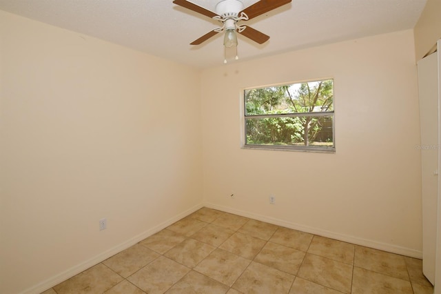 spare room with a ceiling fan, baseboards, and light tile patterned floors