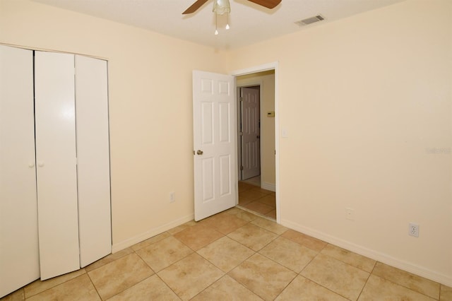 unfurnished bedroom featuring a closet, visible vents, light tile patterned flooring, ceiling fan, and baseboards