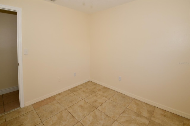 spare room featuring light tile patterned floors and baseboards