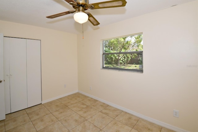 unfurnished bedroom featuring a closet, ceiling fan, baseboards, and light tile patterned floors