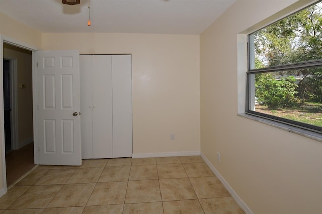 unfurnished bedroom with a closet, baseboards, and light tile patterned floors