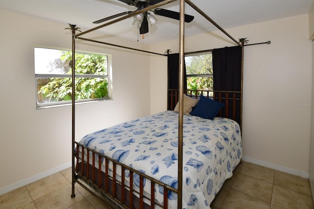 tiled bedroom featuring ceiling fan, multiple windows, and baseboards