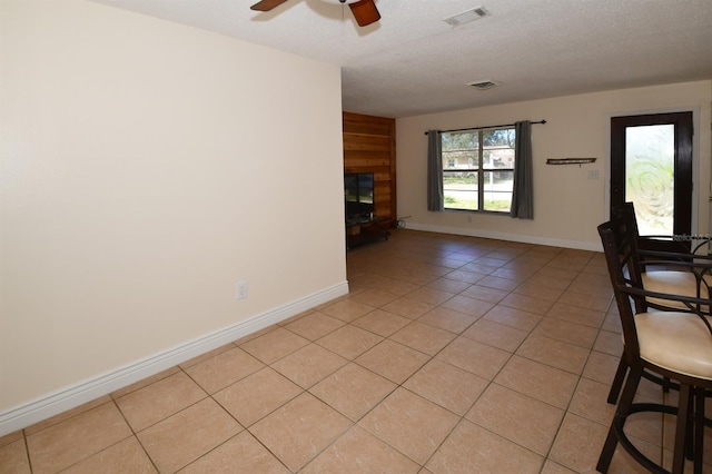 9567 85th St, Seminole, FL 33777 - unfurnished living room with light tile patterned floors, ceiling fan, a fireplace with raised hearth, baseboards, and a textured ceiling
