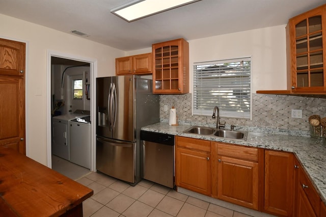 9567 85th St, Seminole, FL 33777 - kitchen with stainless steel appliances, a sink, washing machine and clothes dryer, light tile patterned floors, and backsplash