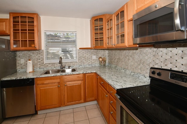 9567 85th St, Seminole, FL 33777 - kitchen featuring stainless steel appliances, a sink, light tile patterned floors, and light stone countertops