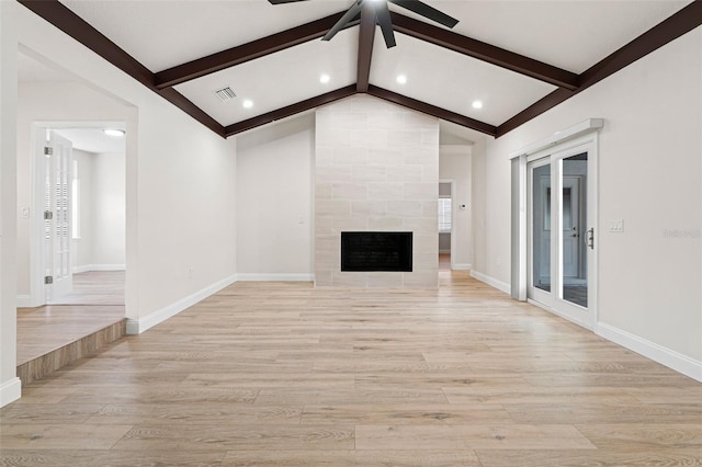 unfurnished living room featuring vaulted ceiling with beams, a tiled fireplace, and light wood-type flooring