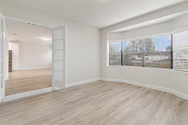 unfurnished room featuring french doors and light hardwood / wood-style flooring