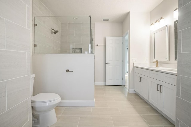 bathroom with a tile shower, tile patterned flooring, vanity, and toilet