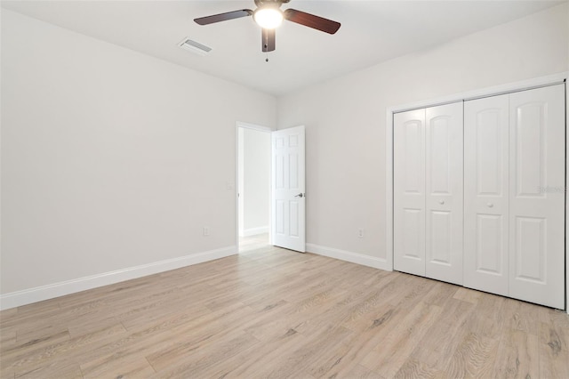 unfurnished bedroom with ceiling fan, light wood-type flooring, and a closet