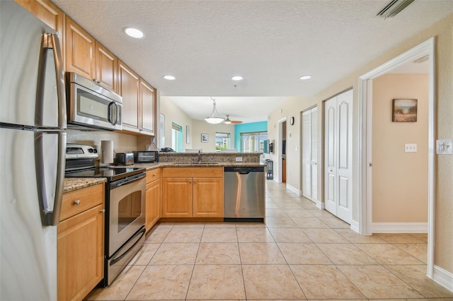 kitchen featuring kitchen peninsula, sink, light tile patterned flooring, and stainless steel appliances