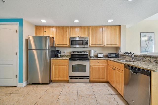 kitchen featuring appliances with stainless steel finishes, a textured ceiling, sink, stone counters, and light tile patterned flooring