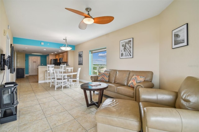 living room with a wood stove, ceiling fan, and light tile patterned flooring