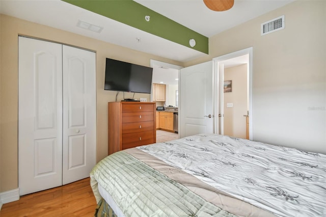 bedroom with light hardwood / wood-style floors, a closet, and ensuite bathroom