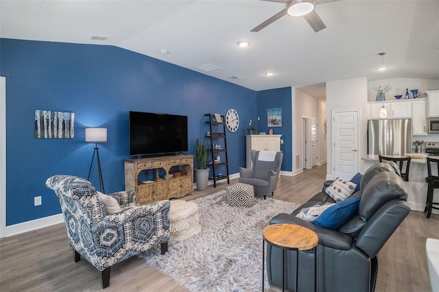 living room with hardwood / wood-style flooring, ceiling fan, and vaulted ceiling