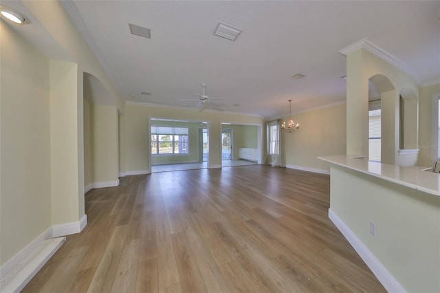 unfurnished living room with ceiling fan with notable chandelier, light wood-type flooring, and crown molding