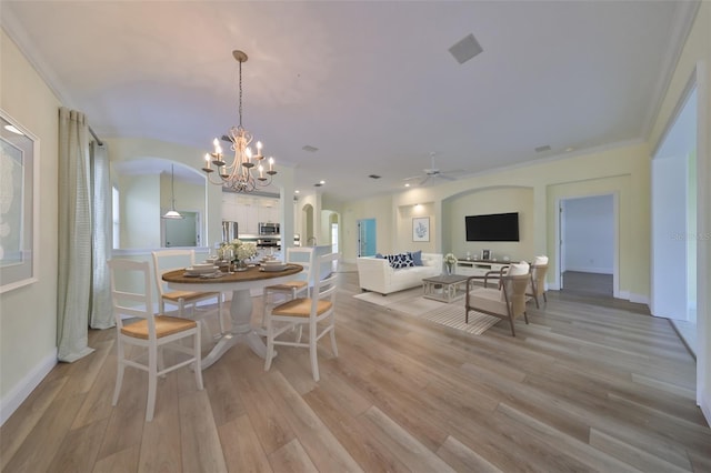 dining area with ceiling fan with notable chandelier, light hardwood / wood-style flooring, and crown molding