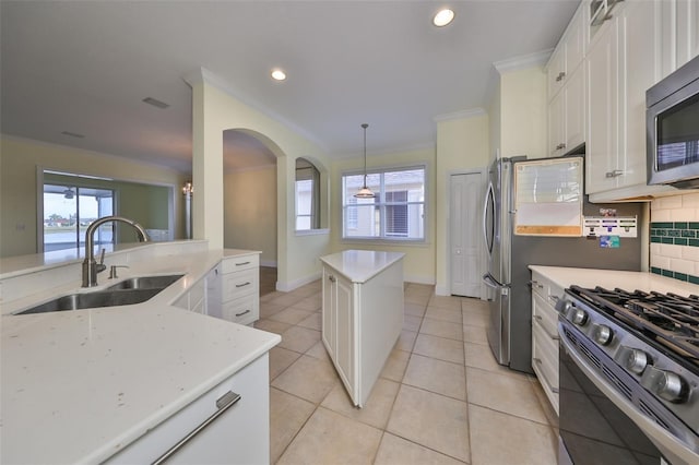 kitchen featuring backsplash, stainless steel appliances, sink, decorative light fixtures, and a kitchen island