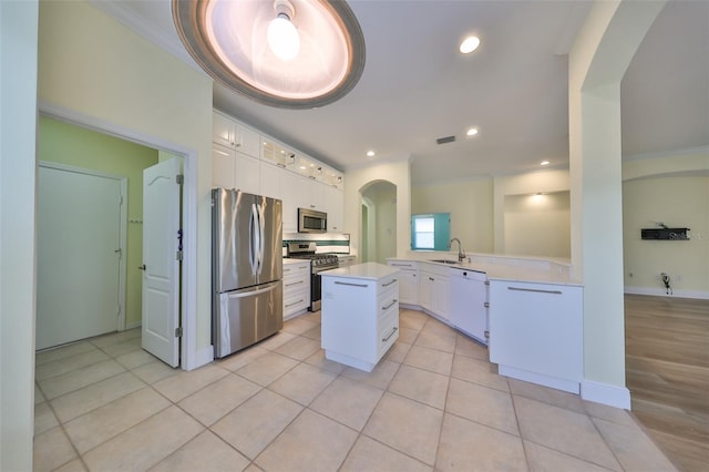 kitchen with kitchen peninsula, a center island, white cabinets, and stainless steel appliances