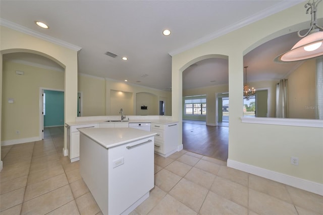 kitchen with a kitchen island, crown molding, sink, an inviting chandelier, and white cabinetry