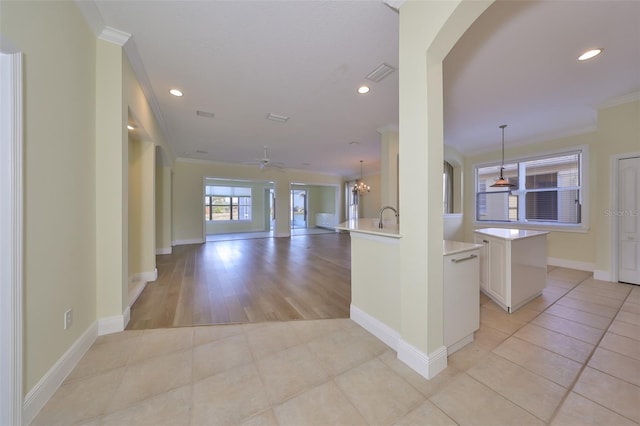 kitchen with ceiling fan, kitchen peninsula, crown molding, pendant lighting, and light wood-type flooring