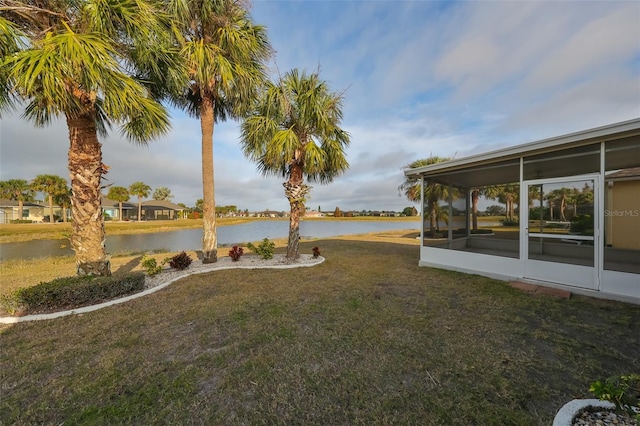 view of yard with a sunroom and a water view