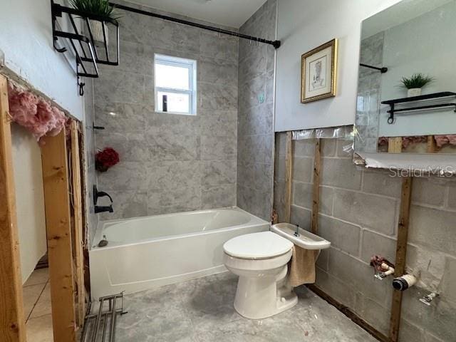 bathroom featuring tiled shower / bath combo and toilet