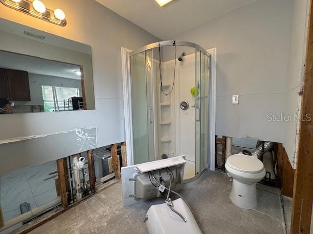 bathroom featuring toilet and a shower with shower door