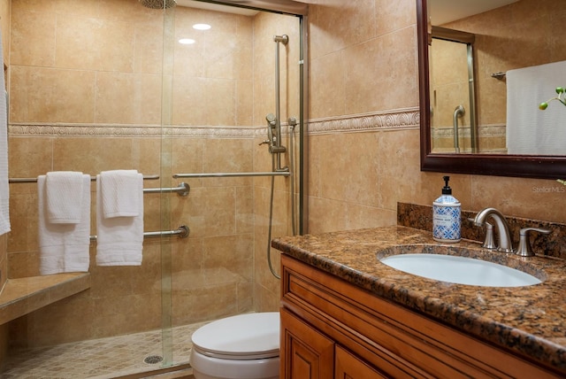 bathroom with toilet, vanity, and a shower with door