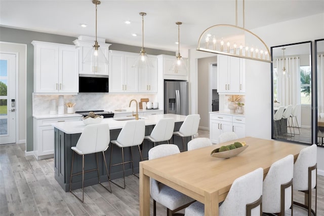 kitchen with white cabinets, stainless steel refrigerator with ice dispenser, and a healthy amount of sunlight