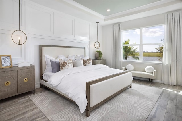 bedroom featuring light hardwood / wood-style floors and a raised ceiling