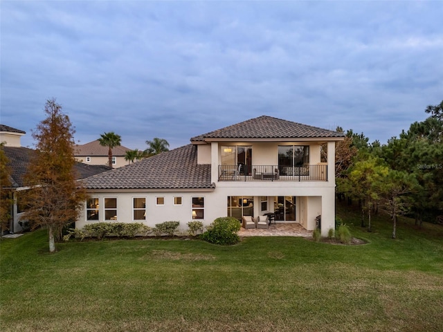 rear view of house featuring a yard, a patio area, and a balcony