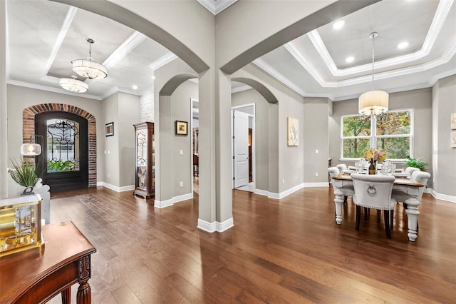 foyer entrance with ornamental molding, dark wood-type flooring, and an inviting chandelier