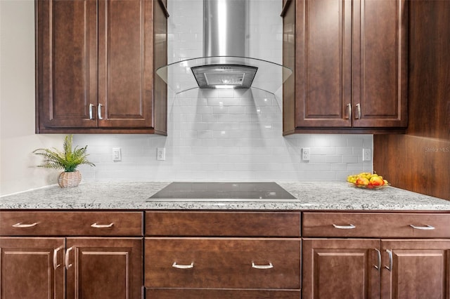 kitchen with backsplash, light stone counters, black electric stovetop, and wall chimney exhaust hood