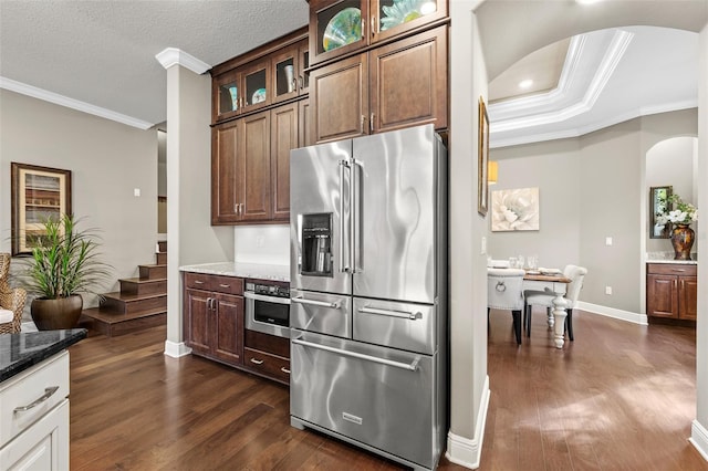 kitchen with stainless steel appliances, dark stone counters, and dark wood-type flooring