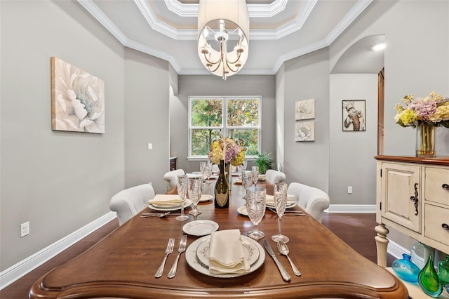 dining space with a raised ceiling, dark hardwood / wood-style flooring, ornamental molding, and a chandelier