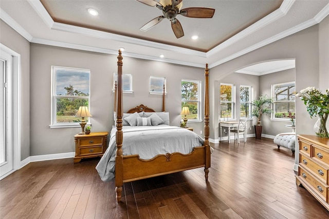 bedroom with a tray ceiling, ceiling fan, crown molding, and dark wood-type flooring