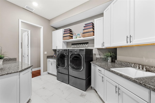 laundry area featuring cabinets, washer and clothes dryer, and sink