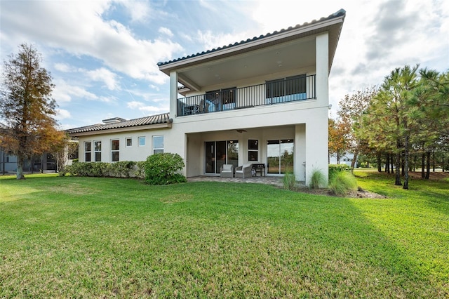 rear view of house with a patio, a balcony, ceiling fan, and a lawn