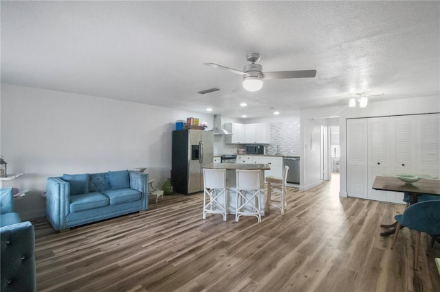 living room featuring hardwood / wood-style floors, ceiling fan, and a textured ceiling