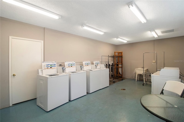 clothes washing area featuring washing machine and dryer and a textured ceiling