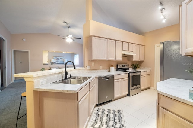 kitchen with lofted ceiling, a kitchen breakfast bar, sink, kitchen peninsula, and stainless steel appliances