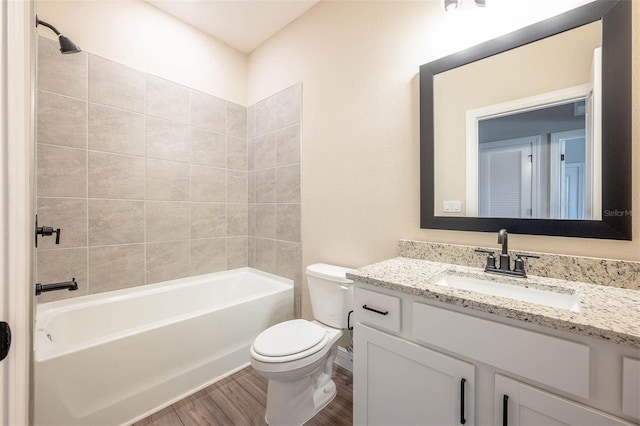 full bathroom featuring vanity, hardwood / wood-style floors, tiled shower / bath combo, and toilet